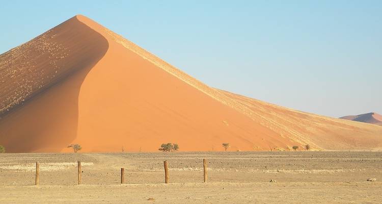 Una gran duna de arena con una sombra nítida en un paisaje desértico.