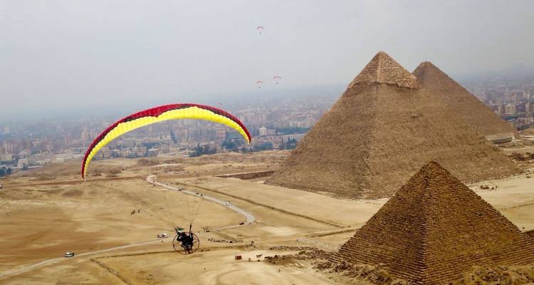 Paraglider above the pyramids with city view.