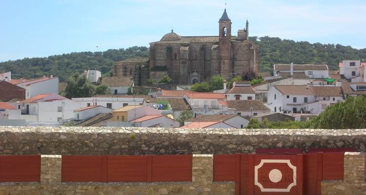 Small town with a church on a hilltop surrounded by vegetation.
