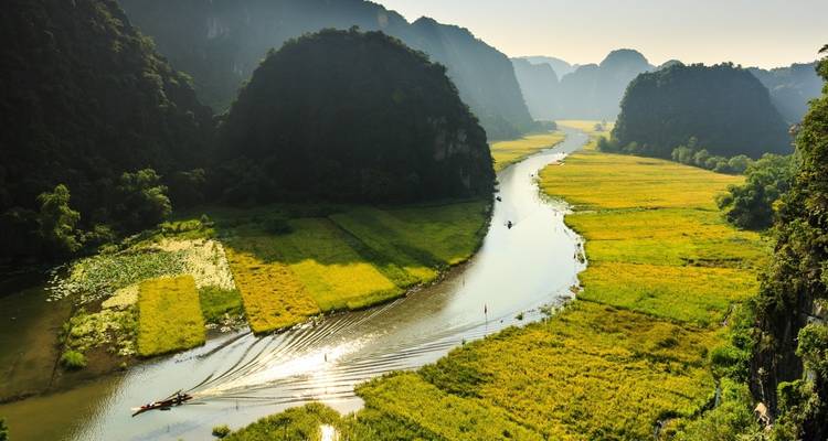 River winding through lush green fields and limestone mountains in Vietnam.