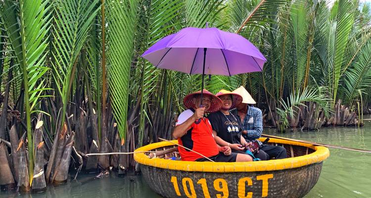 Drei Personen in einem traditionellen Boot auf einer üppigen Wasserstraße.