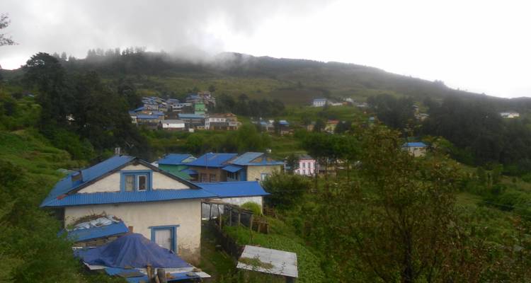 Dorp met blauwgedakte huizen genesteld in een mistige bergvallei.