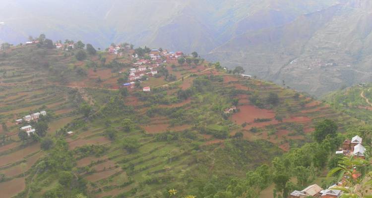 Luchtfoto van terrasvelden en verspreide huizen op hellingen.