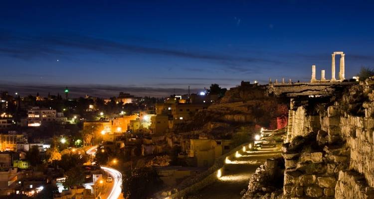 Vue nocturne d'un horizon urbain avec des ruines antiques illuminées.