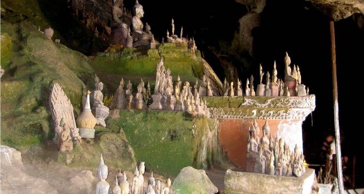Small statues in a cave with moss-covered walls.