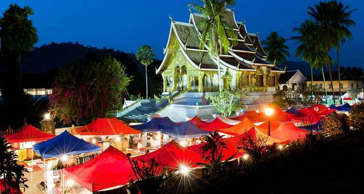 A night market in front of a temple with colorful lights.