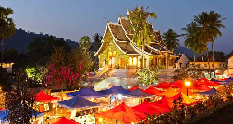 Night market under a beautiful illuminated golden temple.