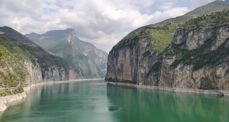 Río esmeralda cortando acantilados verticales altos bajo cielos parcialmente nublados