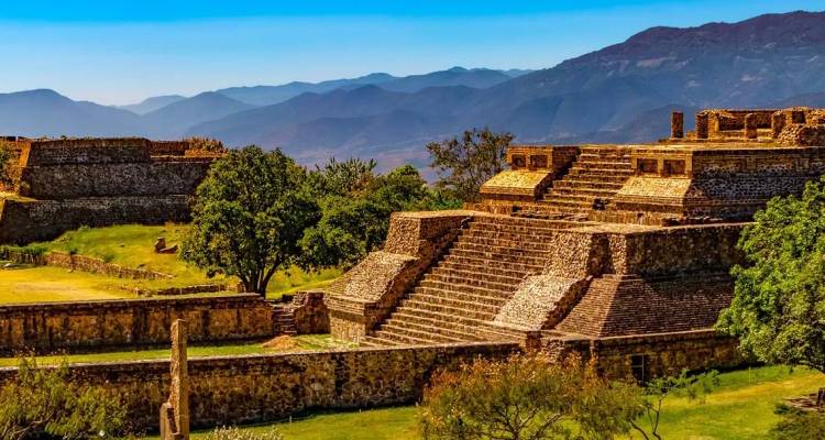 Les temples de pierre et les terrasses de Monte Albán se dressant sur fond de montagnes bleues lointaines à Oaxaca, au Mexique.