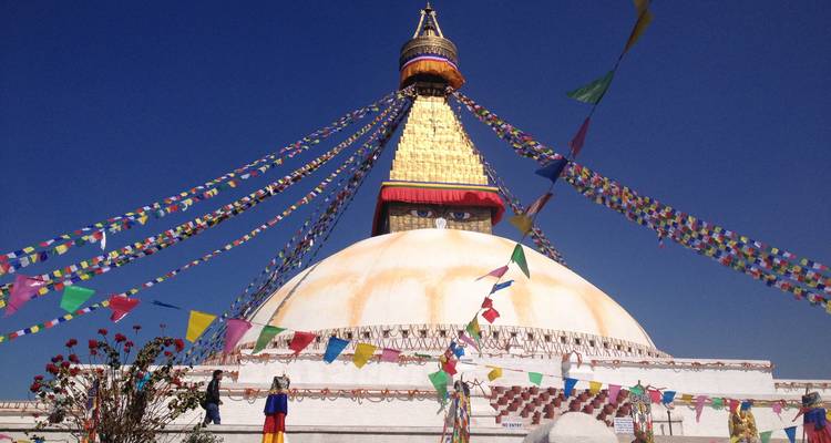 Magnificent stupa with colorful prayer flags against a clear blue sky.