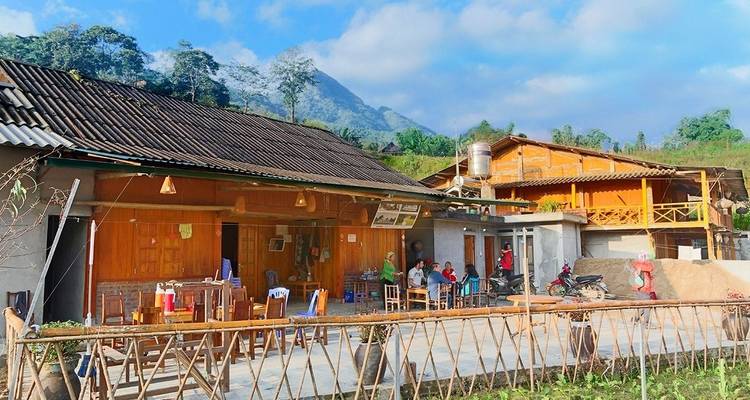 Landelijke omgeving met traditionele houten huizen en een bergachtige achtergrond.