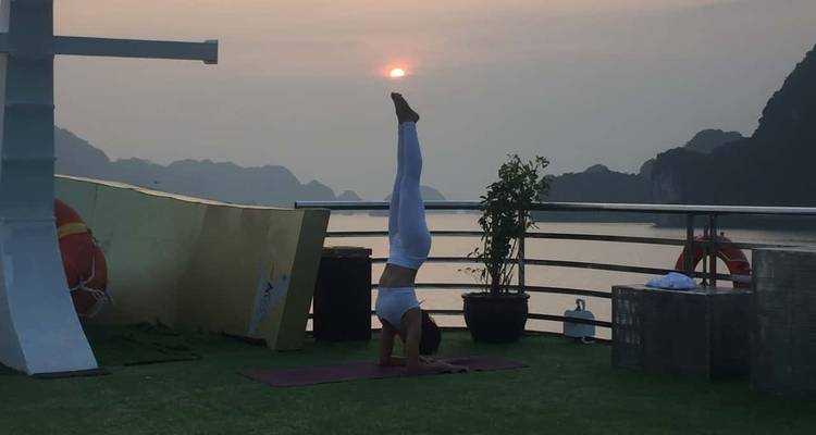 Persoon die yoga beoefent op een terras bij zonsondergang met een schilderachtig water als achtergrond.