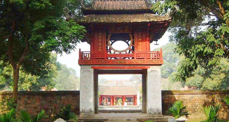Historische poort met ingewikkelde architectuur omringd door weelderig groen.
