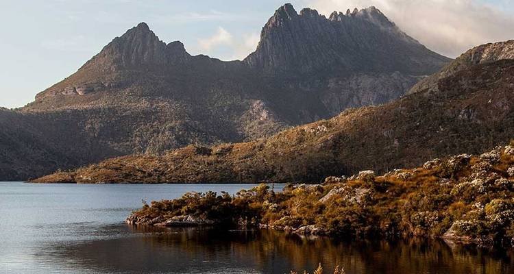 Picos dentados y dramáticos reflejados en un lago tranquilo dentro de la agreste naturaleza salvaje de Tasmania.
