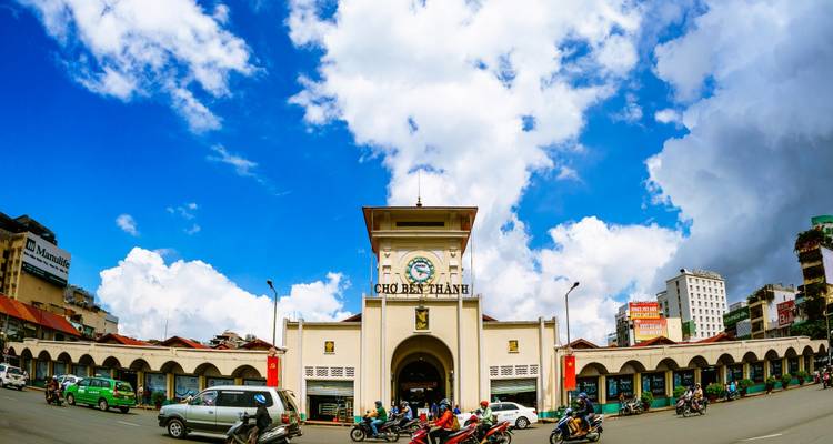 Entrée de marché avec une tour d'horloge et rue animée.