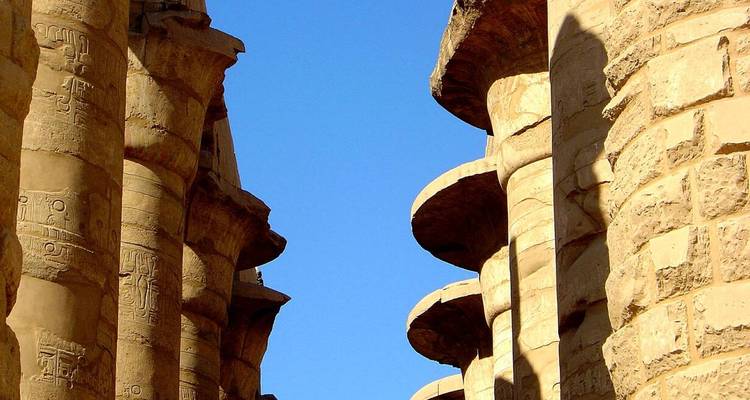 Anciens piliers de pierre avec des hiéroglyphes sous un ciel bleu.
