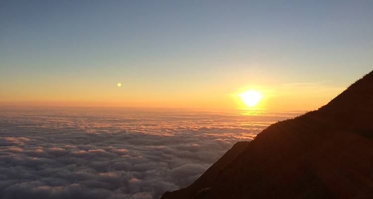 Amanecer dorado sobre un vasto mar de nubes con una silueta de montaña a la derecha