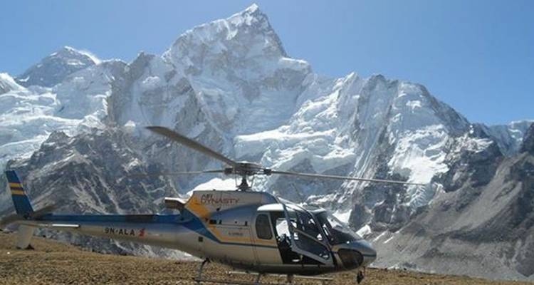 Helikopter geparkeerd met besneeuwde bergen op de achtergrond.