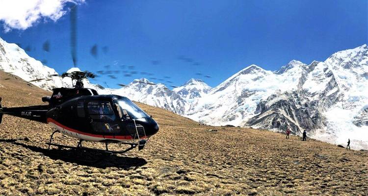 Helikopter op de grond met besneeuwde bergen op de achtergrond.