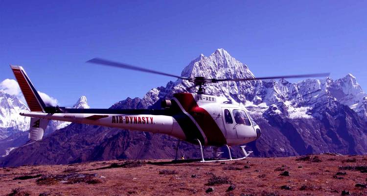 Helikopter geparkeerd op een bergplateau met een besneeuwde achtergrond.