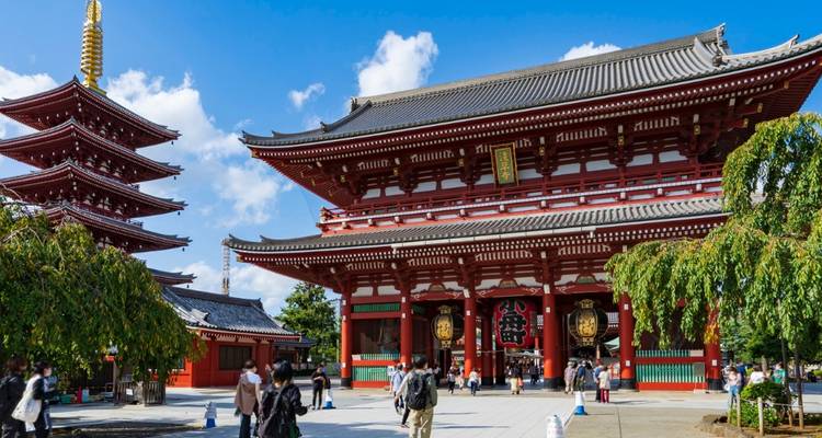 Des foules explorant les halls d'un rouge éclatant et la pagode de cinq étages du temple Sensoji de Tokyo par une journée ensoleillée