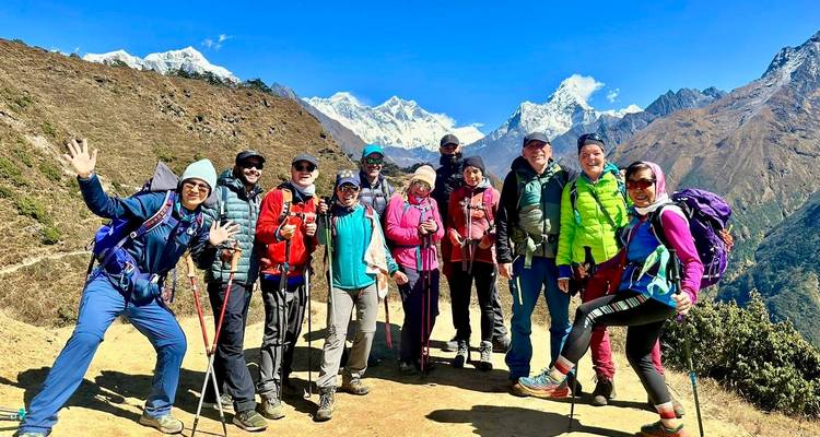 Group of trekkers posing with mountain peaks in the background.