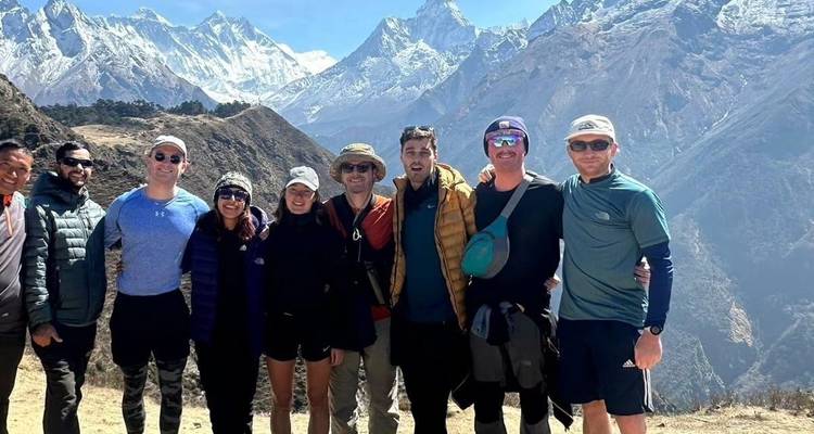 Group of hikers posing with mountain peaks in the background.