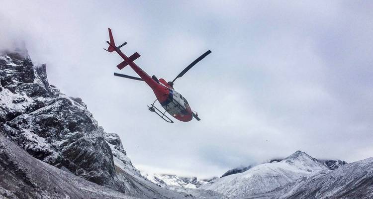 Helicopter flying in a snowy mountainous area.