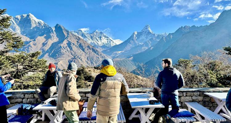 People sitting at tables outdoors with a view of mountains.