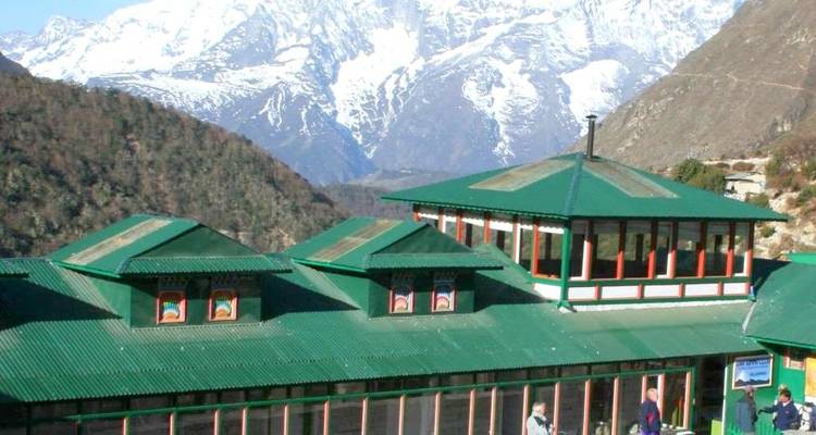 Lodge with green roof amidst mountains.