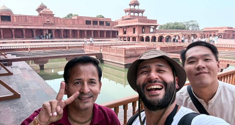 Tres personas tomándose una selfie frente a un edificio histórico con agua