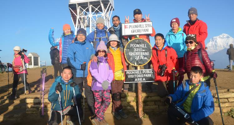 Gruppenfoto am Aussichtspunkt Poon Hill mit verschneiten Gipfeln im Hintergrund.