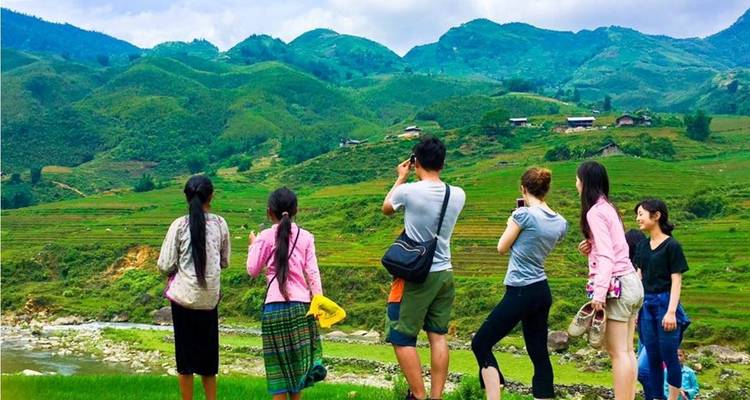 Group of travellers and local women pause to photograph terraced hills in the highlands