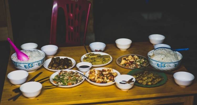 Traditional Vietnamese meal spread with rice, spring rolls, vegetables and sauces on a wooden table