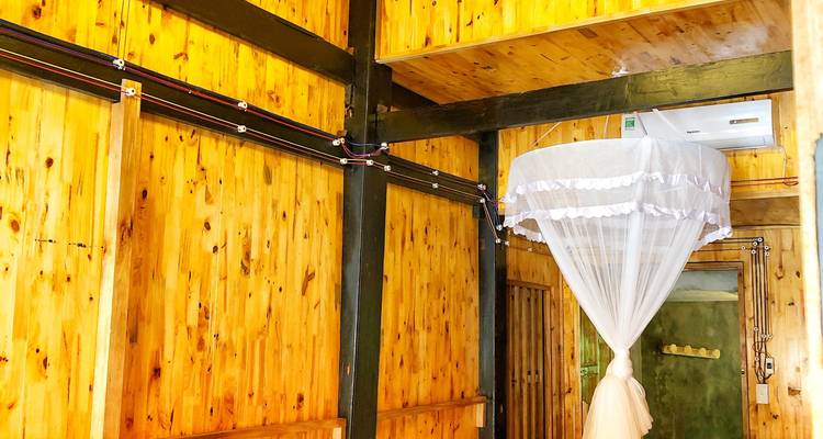 Simple wooden guesthouse interior with a mosquito-netted bed and timber walls