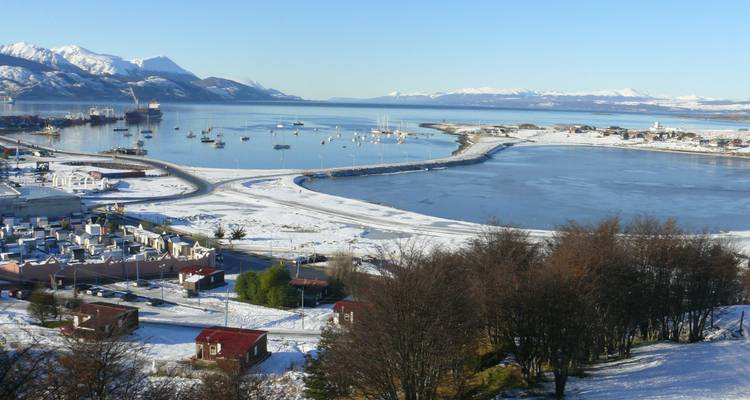Paysage enneigé avec une baie et des montagnes en arrière-plan.