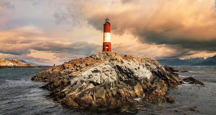Phare sur une île rocheuse avec des ciels dramatiques.