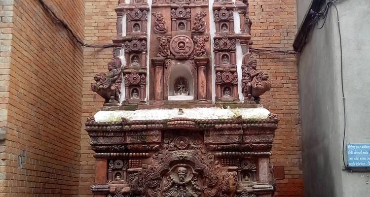 An intricately carved stone structure against a brick wall.