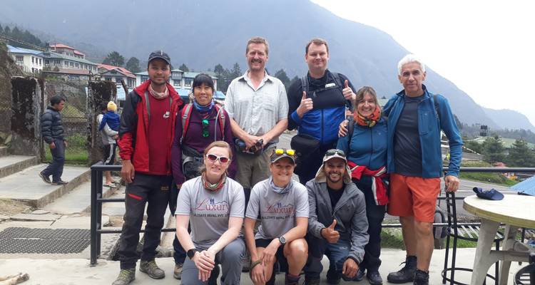 Große Gruppe posiert im Freien mit Bergen im Hintergrund.