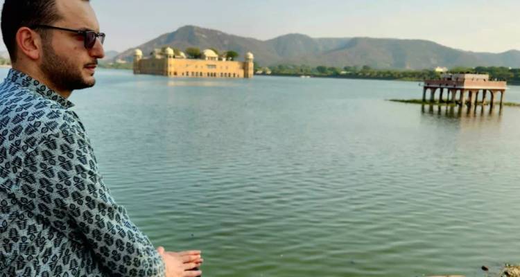 Un homme regardant le palais Jal Mahal sur un lac.