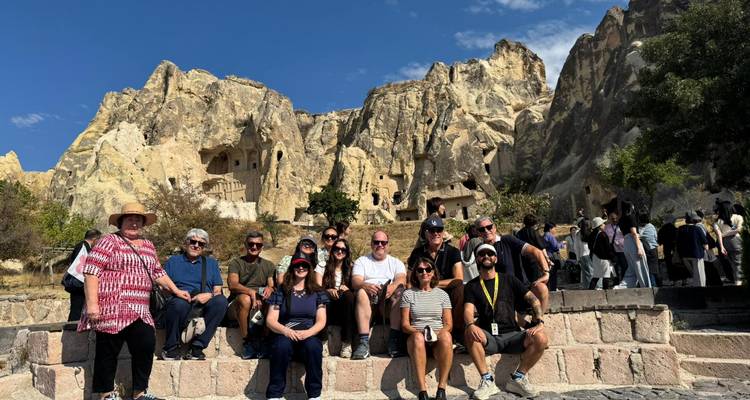 Group photo in front of rock formations and a historic site.