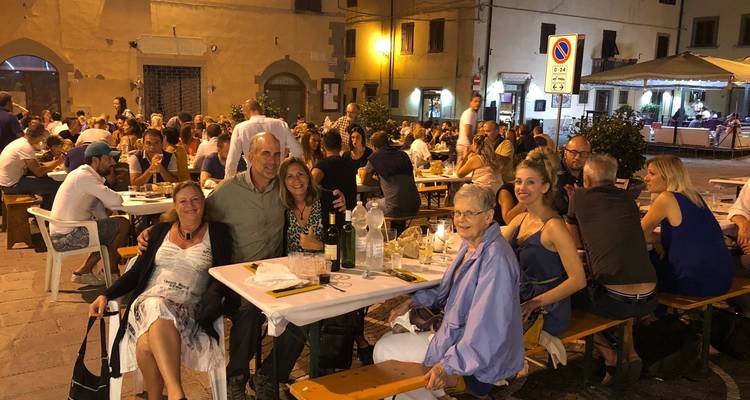 Groupe de personnes dînant en plein air sur une place publique.
