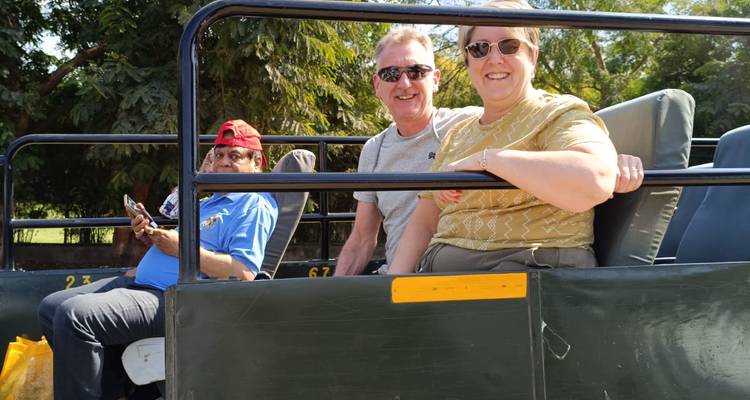 People sitting on a safari vehicle under a sunny sky.