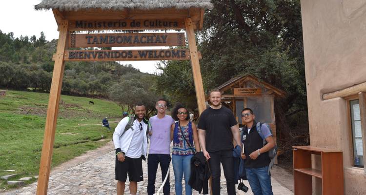 Groupe de personnes debout sous un panneau de bienvenue à Tambomachay.