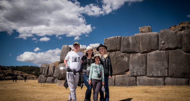 Familia posando frente a grandes ruinas de piedra.