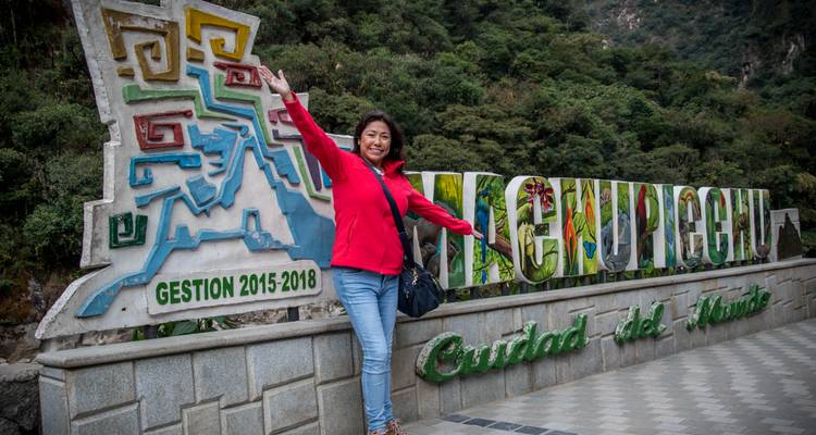 Mujer posando frente a un letrero colorido de Machu Picchu.