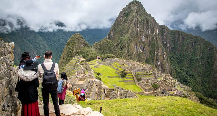 Los visitantes admiran la antigua ciudad de piedra de Machu Picchu desde un mirador elevado envuelto en niebla.