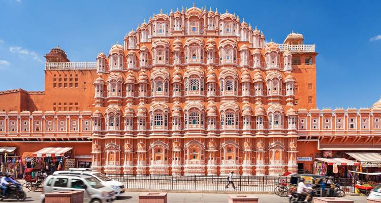 A stunning view of the Hawa Mahal with people and vehicles in front.