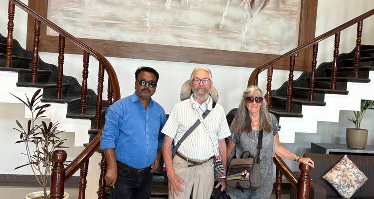 Three travelers standing in a hotel lobby with a grand wooden staircase behind them