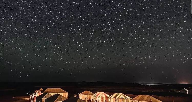 Heldere sterrenhemel boven kleurrijke woestijnkamptenten.
